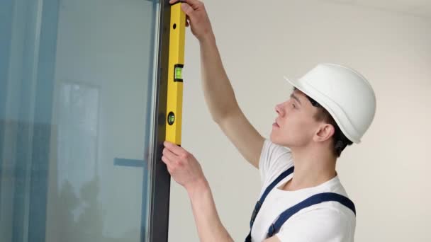 창문 설치를 하는 마법사는 물주머니로 작업의 품질을 확인 — 비디오