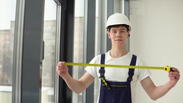 El instalador de ventanas mide las dimensiones del marco de la ventana con una cinta métrica — Vídeo de stock