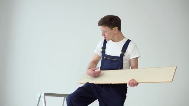 L'installateur au sol tient un parquet ou une planche de vinyle et imite le jeu de la guitare — Video