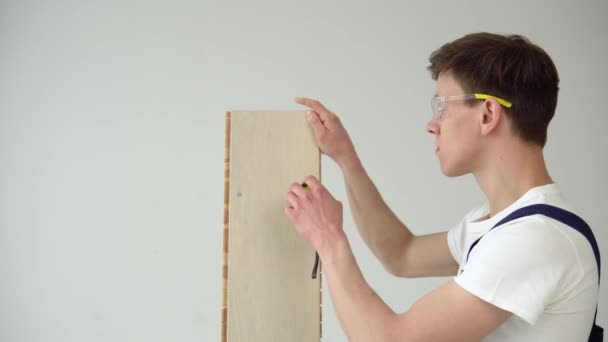 L'installateur au sol tient un parquet ou une planche de vinyle et installe le plancher — Video