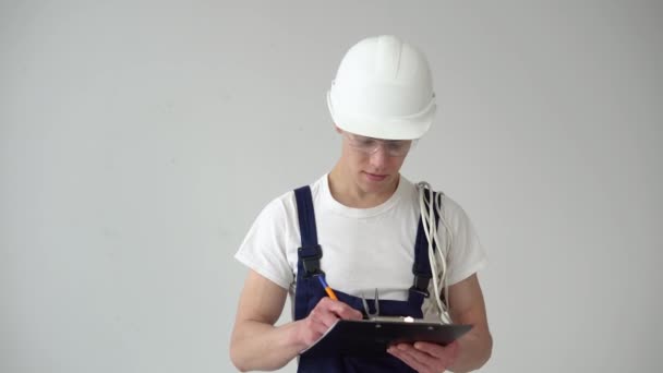 Maestro o asistente toma notas sobre un fondo blanco de la pared durante las reparaciones en la casa — Vídeo de stock