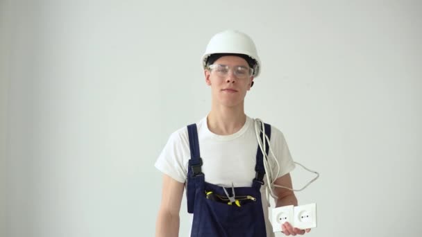 El electricista sostiene los enchufes en su mano y mira hacia adelante — Vídeos de Stock