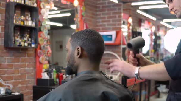 Le coiffeur sèche les cheveux avec un sèche-cheveux professionnel moderne au client à l'étape finale de la coupe de cheveux. les dernières technologies de soins capillaires — Video
