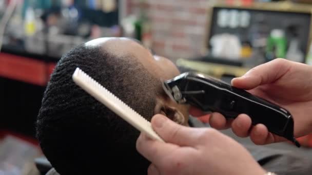 Peluquería hace para el cliente un corte de pelo con un cortador — Vídeos de Stock
