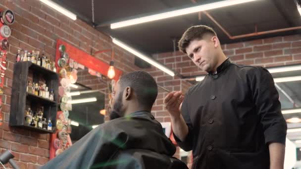 Peluquería corta el cabello de los clientes con tijeras. Un hombre en la peluquería. La profesión de peluquero — Vídeo de stock