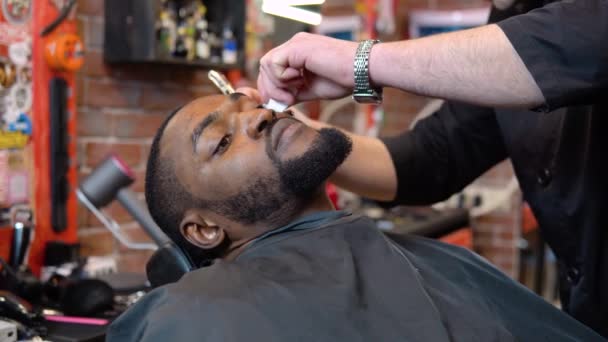 Der Friseur schneidet den Kunden den Bart mit einem Haarschneider. Der Mann im Friseurladen. Der Beruf des Friseurs. — Stockvideo