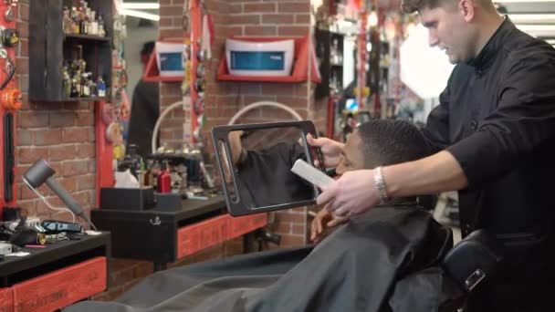 O cabeleireiro mostra ao cliente o resultado do corte de cabelo e barbear no espelho da mão — Vídeo de Stock