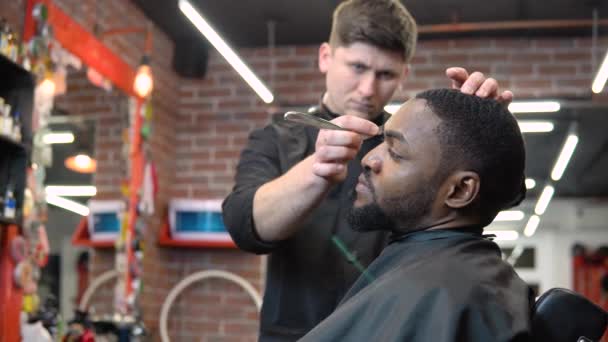 Перукар вирізає клієнтську бороду за допомогою затискача. Чоловік у перукарні. Професія перукаря . — стокове відео