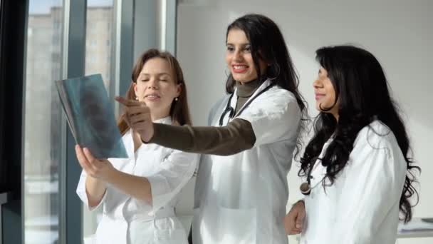 Farklı ırktan üç kadın doktor röntgeni analiz ediyor. — Stok video