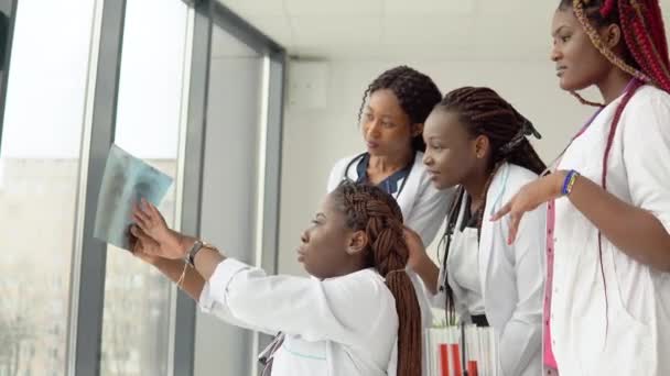 Junge Ärzte untersuchen am Tisch ein Röntgenbild — Stockvideo
