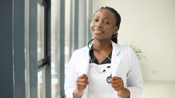 Afroamerikanische Ärztin oder Krankenschwester steht im Anzug in der Klinik und blickt in die Kamera — Stockvideo