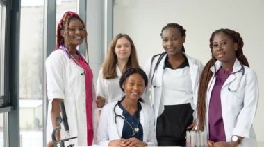 Farklı ırklardan bir grup genç doktor bir masada oturmuş sohbet ediyorlar.