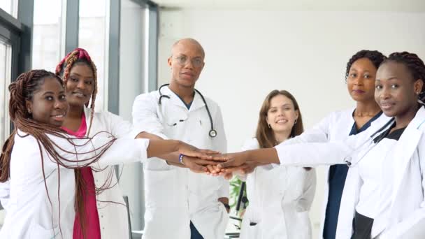 Zespół lekarzy, w tym kobiet i mężczyzn różnych narodowości, czyni gest jedności. — Wideo stockowe