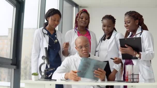 Пять африканских американских врачей мужчина и женщина осматривают рентген стоя за столом — стоковое видео
