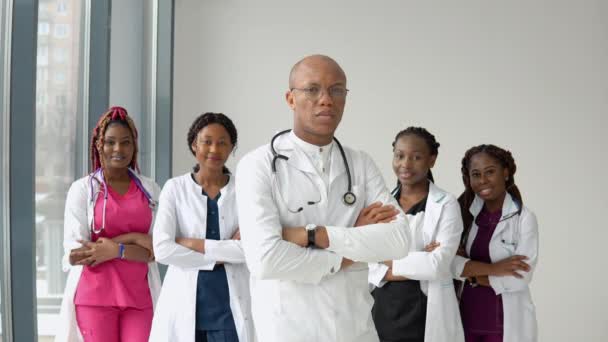 Egy csapat orvos, afro-amerikai férfi és nő, a kamera előtt állnak, és egyenesen előre néznek egy klinikán. — Stock videók