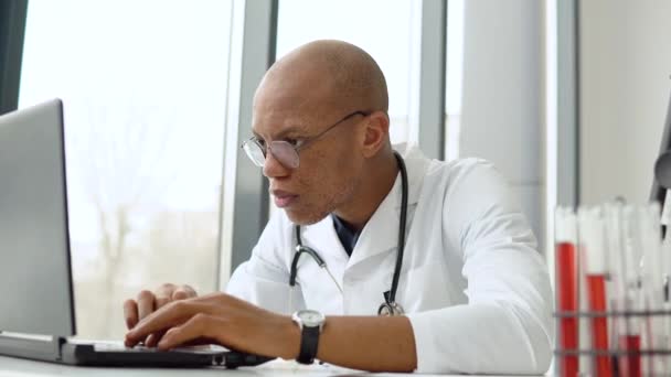 Junger afrikanisch-amerikanischer Arzt am Schreibtisch. Entwicklung des covid 19 Impfstoffs — Stockvideo