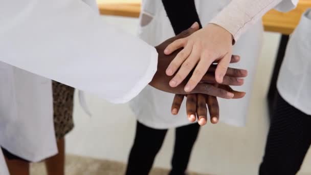 Команда лікарів, включаючи жінок і чоловіків різних національностей, роблять жест єдності. Крупним планом зйомка рук — стокове відео