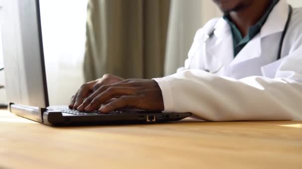 Nahaufnahme der Hände eines afrikanisch-amerikanischen Arztes, der in der Klinik am Laptop arbeitet — Stockvideo