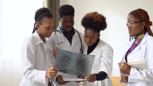 Eine Gruppe von vier afrikanisch-amerikanischen Ärzten diskutiert eine Röntgenaufnahme eines Patienten — Stockvideo
