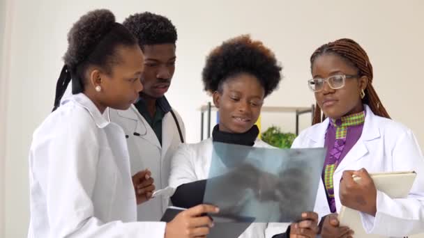 Un grupo de cuatro médicos afroamericanos discuten una radiografía de un paciente — Vídeos de Stock