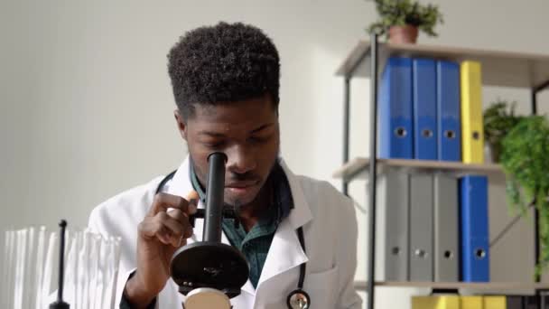 Afrikanischer Arzt arbeitet mit Erregerproben. Junge afrikanisch-amerikanische Wissenschaftlerin im Labor unter dem Mikroskop — Stockvideo