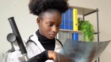 Masadaki röntgende çalışan Afrikalı Amerikalı kadın doktor.