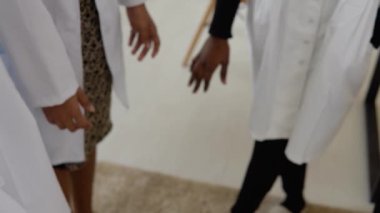 Aralarında farklı milletlerden kadın ve erkeklerin de yer aldığı bir doktor ekibi birlik jesti yapıyor. Ellerin yakın plan çekimi