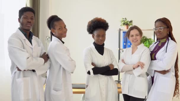 一组医生，包括来自不同国家的男男女女，站在诊所里看着摄像机。大学的医科学生实习生 — 图库视频影像
