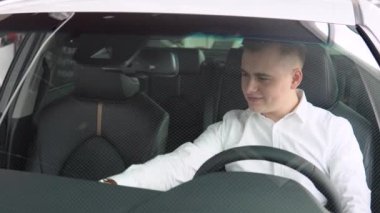 Bir araba galerisinde prestijli lüks bir arabada genç şık bir adam. Otomobil işi, araba satışı.