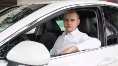 Yeni arabasının anahtarlarını galeride gösteren mutlu ve şık bir adam. Otomobil işi, araba satışı.