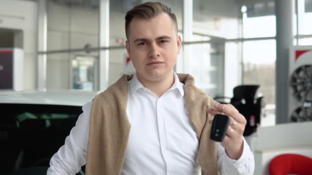 Elegante homem elegante mostrando as chaves de seu novo carro na concessionária — Vídeo de Stock
