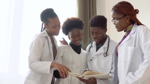 Kitapları olan Afrikalı tıp öğrencileri hastanede bir şey tartışıyorlar. Klinikteki bir grup Afrikalı Amerikalı genç doktor — Stok video