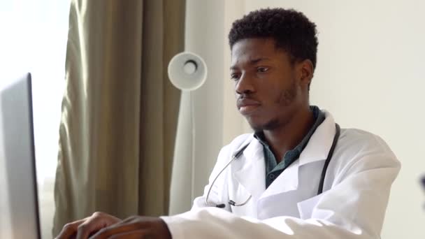 Giovane medico afro-americano di sesso maschile che lavora su laptop in clinica — Video Stock