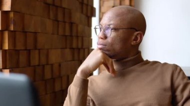 Bir kafede çalışma gününün estetiği. Serbest, uzaktan kumandalı. Deve kaşmir kazaklı Afrikalı genç bir adam. Şık, yakışıklı iş adamı. Videoportrait