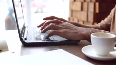 Ciddi ifadeleri olan Afro-Amerikan bir adam evde dizüstü bilgisayar ve belgelerle çalışıyor. Salgın. Kilitlenme. Eller yukarı.