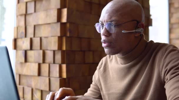 Серьезный молодой африканский мужчина, работающий в кафе — стоковое видео
