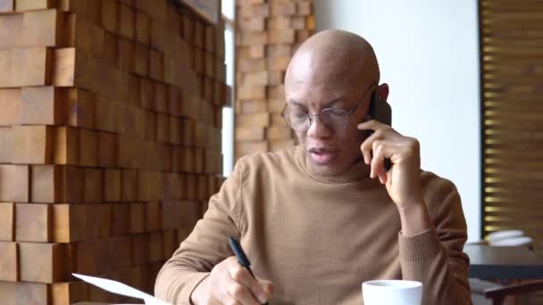 Um afro-americano faz algumas anotações durante a chamada. Estética da cor do caramelo. Homem elegante em roupa casual — Vídeo de Stock