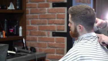 Genç bir adam berber dükkanında saçıyla ilgilenir.