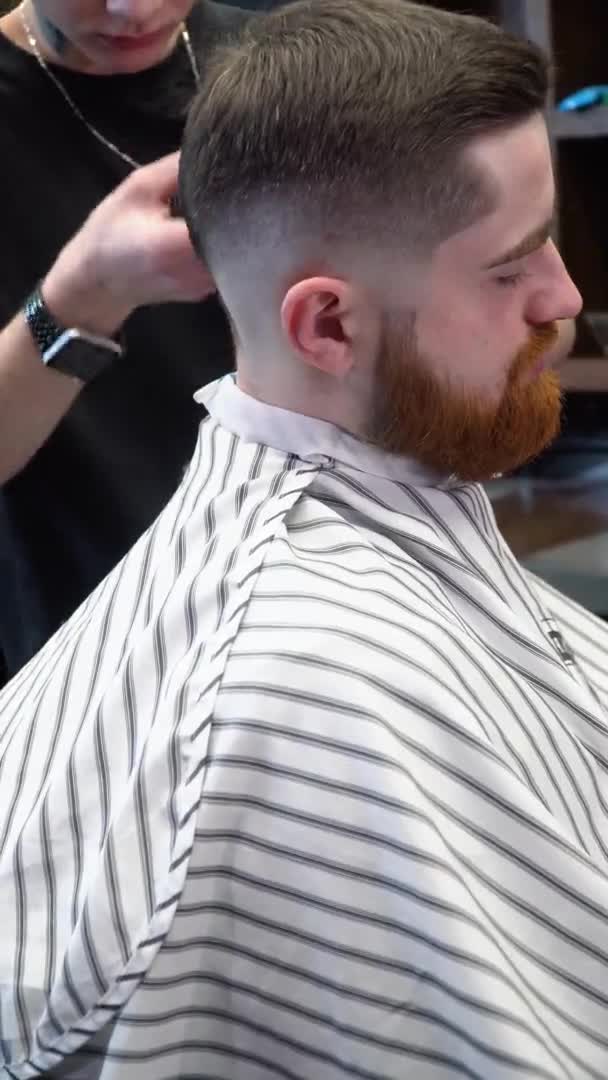 Coiffeur fait un design de coupe de cheveux sur le dos de la tête des clients. Vidéo verticale — Video