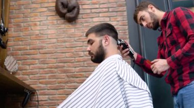 Bir adam şık bir berber dükkanında saç tıraşı olur. Yan görünüm