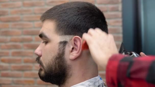 Egy fiatal srác haját levágják egy borbélyüzletben. Fehérbőrű férfi — Stock videók