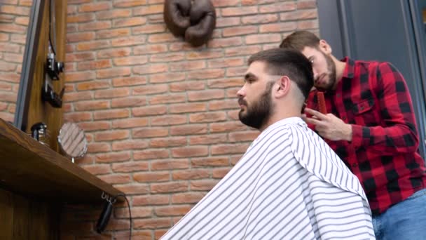 Un uomo si fa tagliare i capelli in un elegante barbiere. Vista laterale — Video Stock