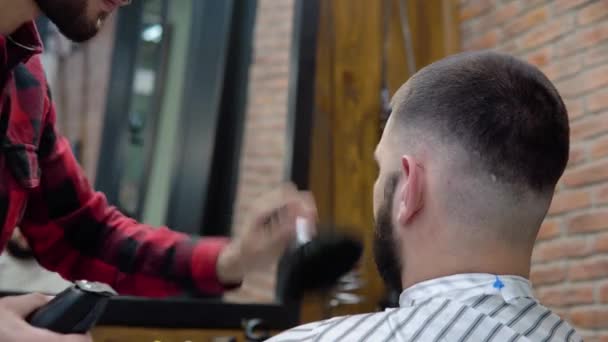 De jonge kapper maakt gebruik van een trimmer en een zachte borstel tijdens het kapsel. Schoonheidsdiensten van de hoogste kwaliteit — Stockvideo