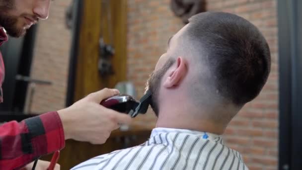 La peluquería trabaja en el estilo de los clientes en una moderna barbería con estilo — Vídeos de Stock