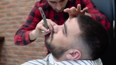 Berber dükkanında sakal kesimi. İki genç adam. Şık görünüş
