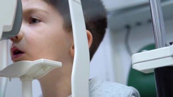 Chłopiec w klinice okulistycznej przeprowadza test wzroku na specjalnym sprzęcie. — Wideo stockowe