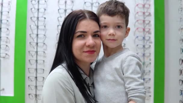 Mladá žena s dítětem, matkou a synem na pozadí výlohy s brýlemi v obchodě s optikou. Optika, optický obchod — Stock video
