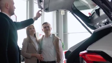 Profesyonel araba satıcısı, ilgili alıcılara, motor fuarında bagajı açık olan lüks bir arabadan bahsediyor.