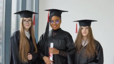 Farklı ırktan üç kız öğrenci ellerinde bir diplomayla. Yurtdışında yüksek öğrenim. Farklı milletlerden üç öğrenci.