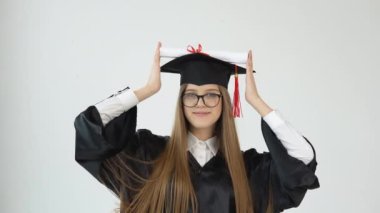 Master 's Pelerin' deki üniversitede okuyan genç bir kadın diplomasını ellerinin damlanın üzerinde buduyor ve kameraya hayret ediyor. Beyaz arkaplanda bir portre